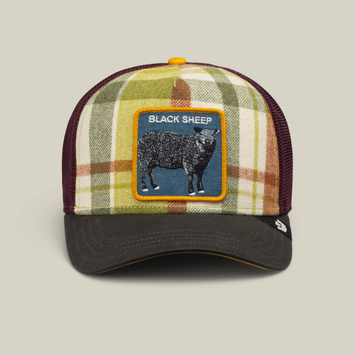 Introducing the Brit Sheep trucker hat from Goorin Bros.—a fall-ready plaid cap featuring a black bill, mesh back, and a distinctive BLACK SHEEP patch on the front. Crafted with a wool blend, this playful accessory brings rebellious charm to your autumn wardrobe.