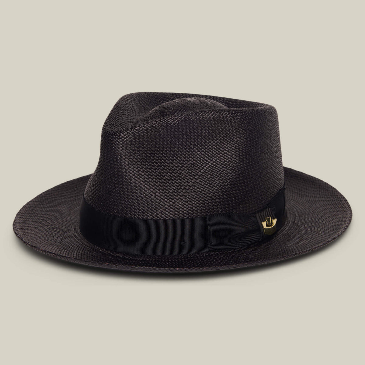 The Goorin Bros. John Sr. is a dark brown woven toquilla fedora with a wide brim, black ribbon band, and small gold pin, stylishly displayed on a light beige background for sun protection.