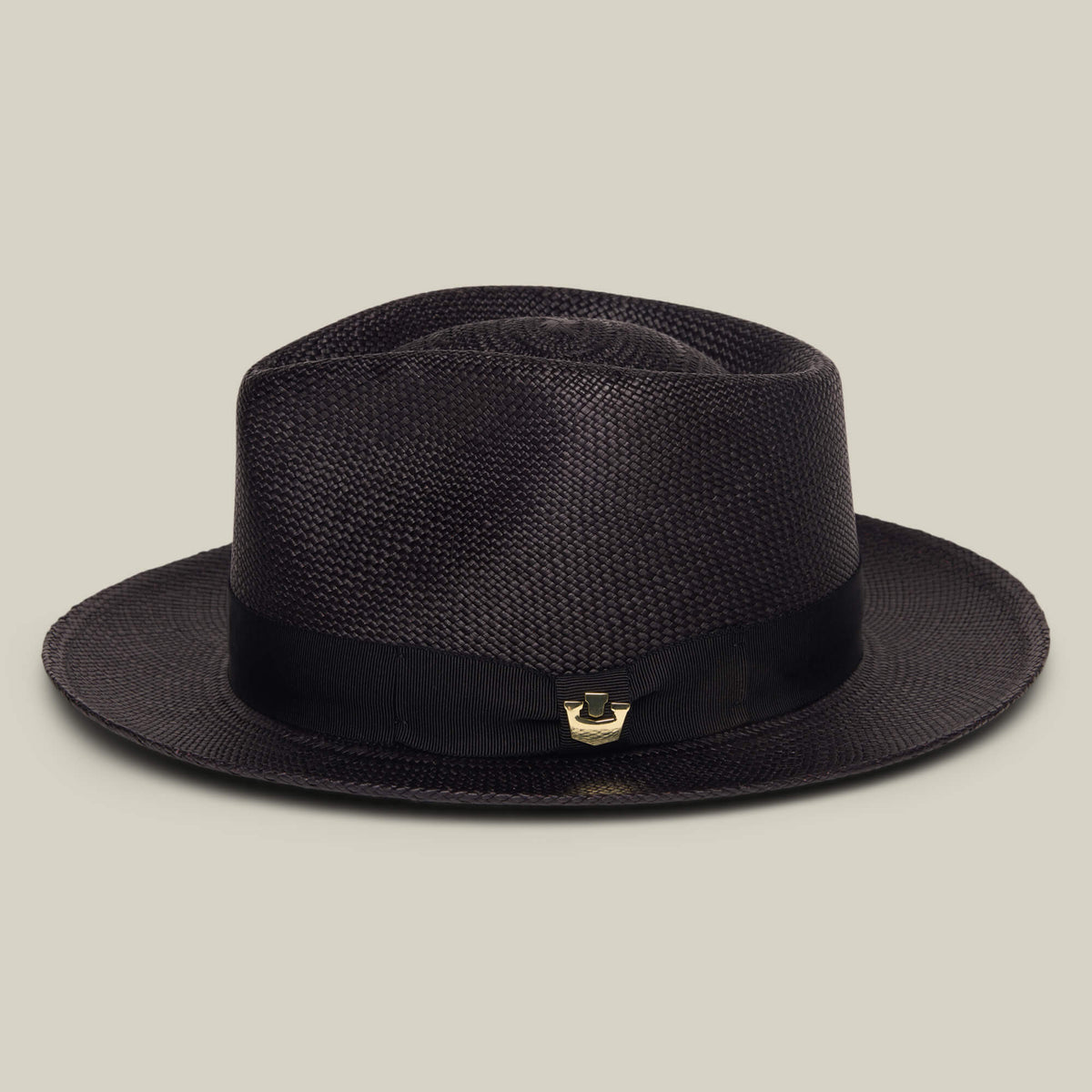 The John Sr. by Goorin Bros. is a dark brown toquilla teardrop fedora with a wide brim, black ribbon band, 50 UPF sun protection, and a small gold accent, shown on a plain light background.