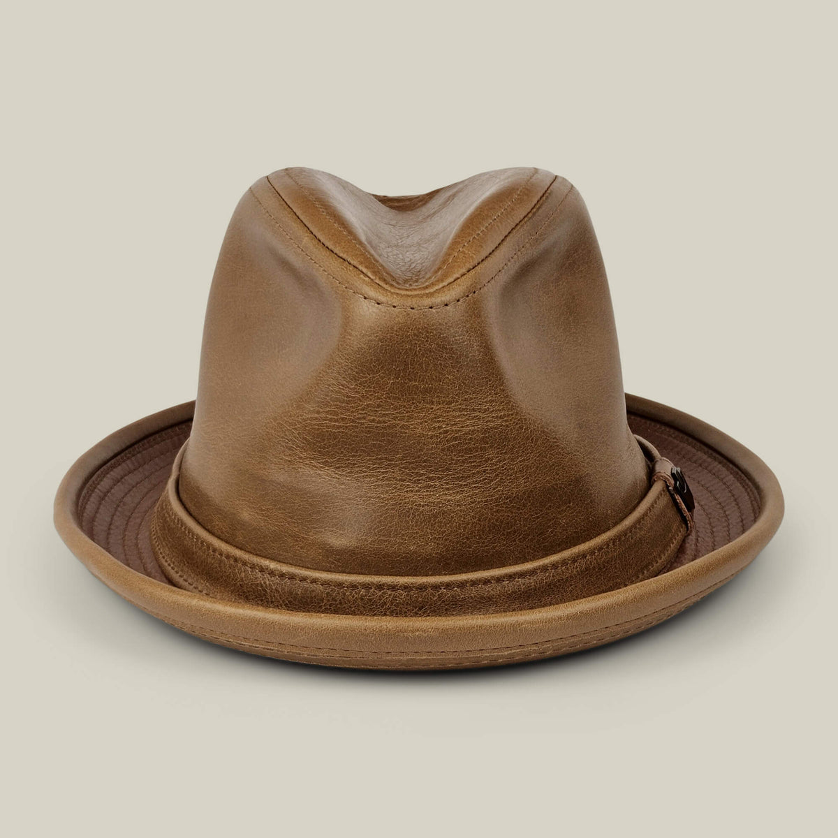 The Goorin Bros. Noble Park fedora in amber tan features a dented crown and wide, slightly upturned brim. Handmade in the USA, it's showcased against a plain beige background.
