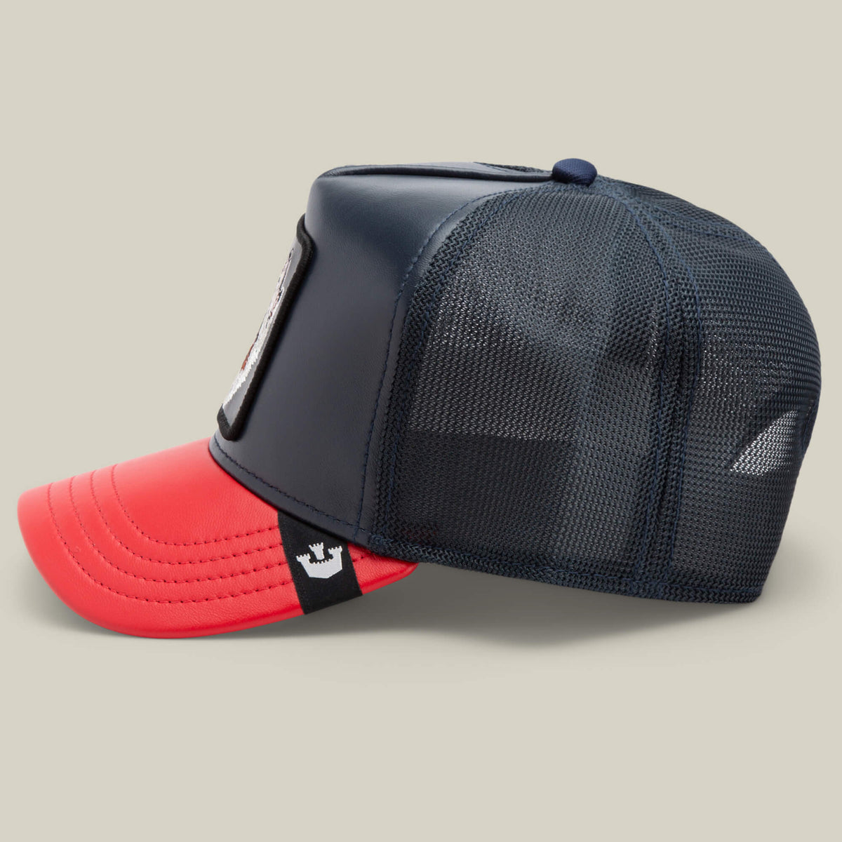 The Farm’s Shleather Wolf hat features navy mesh, a red bill, and a rectangular front patch—shown in side profile on a neutral backdrop—ideal for adding bold style to your fashion lineup.