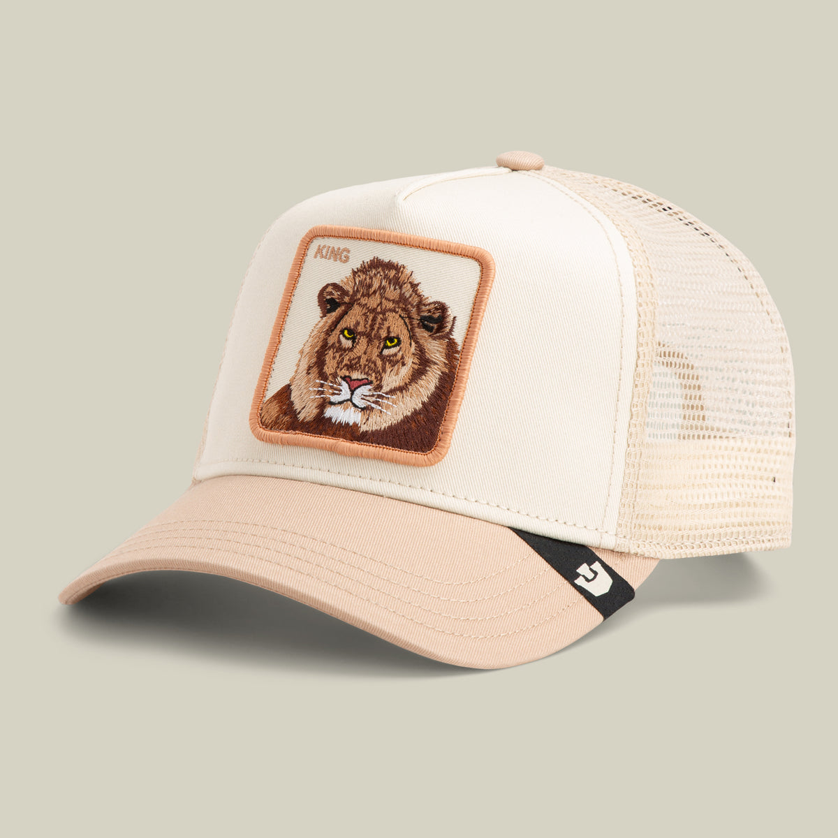 The Goorin Bros. King Trucker hat features beige and tan mesh panels with a front patch displaying a lion's face and the word "KING" above it.