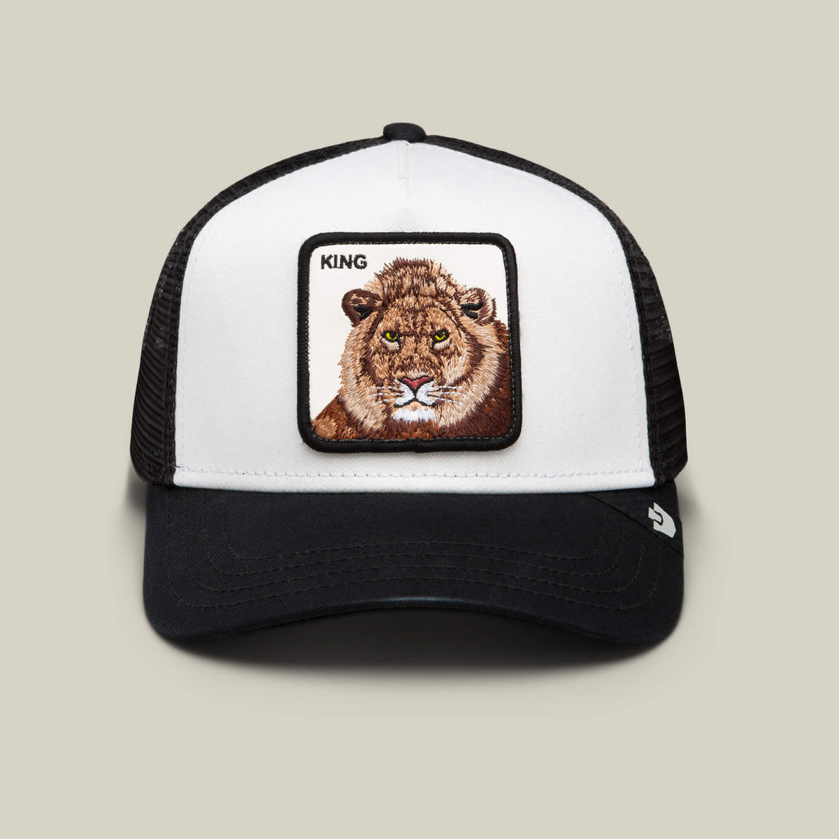 The King Trucker by Goorin Bros. is a black and white hat with a bold lion patch and "KING" above it, ideal for power dressing, shown against a simple background.