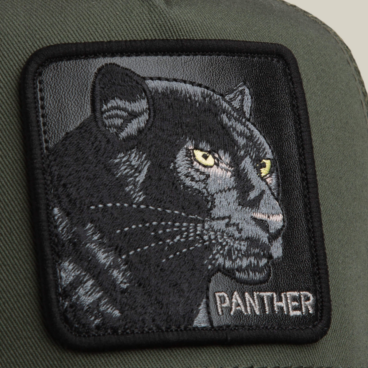 The Panther Trucker by Goorin Bros. features a green fabric surface with a stitched patch of a black panther’s face and "PANTHER" in bold at the bottom right—ideal for fans of classic panther hat styles.