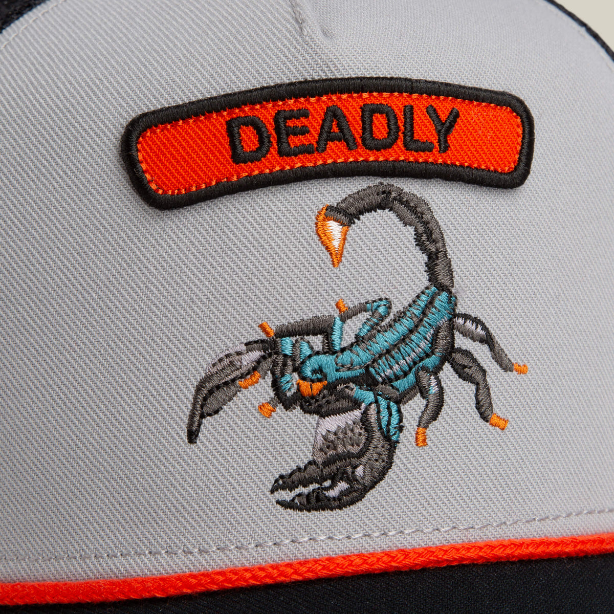 A close-up of the Goorin Bros. Pop Rocker Scorpion hat, featuring an embroidered scorpion with a "DEADLY" patch above it and a curved brim for a stylish touch.