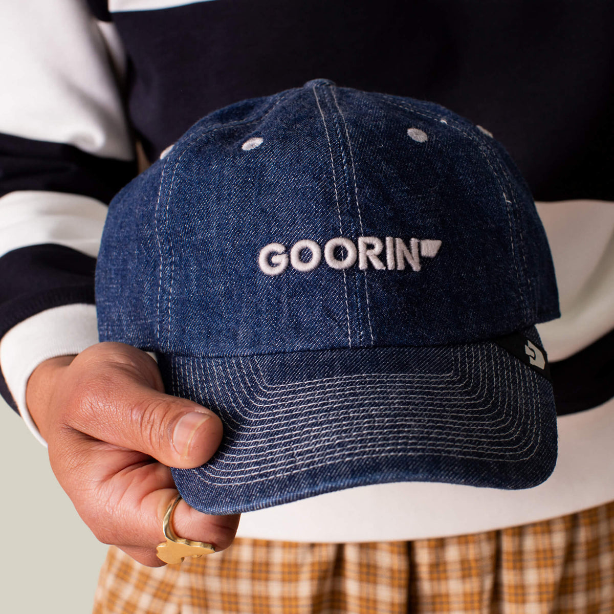 A person holds the Papa Core Denim low profile blue denim hat by Goorin Bros., featuring the GOORIN wordmark embroidered in white on the front.