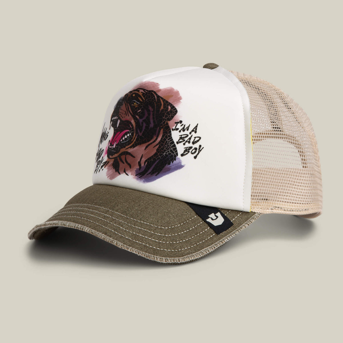 The Bad Boy Disruption trucker hat by Goorin Bros. features a hand-illustrated Rottweiler insignia on a white front panel, olive green bill, and beige mesh back, with "IM A BAD BOY" text for bold attitude.