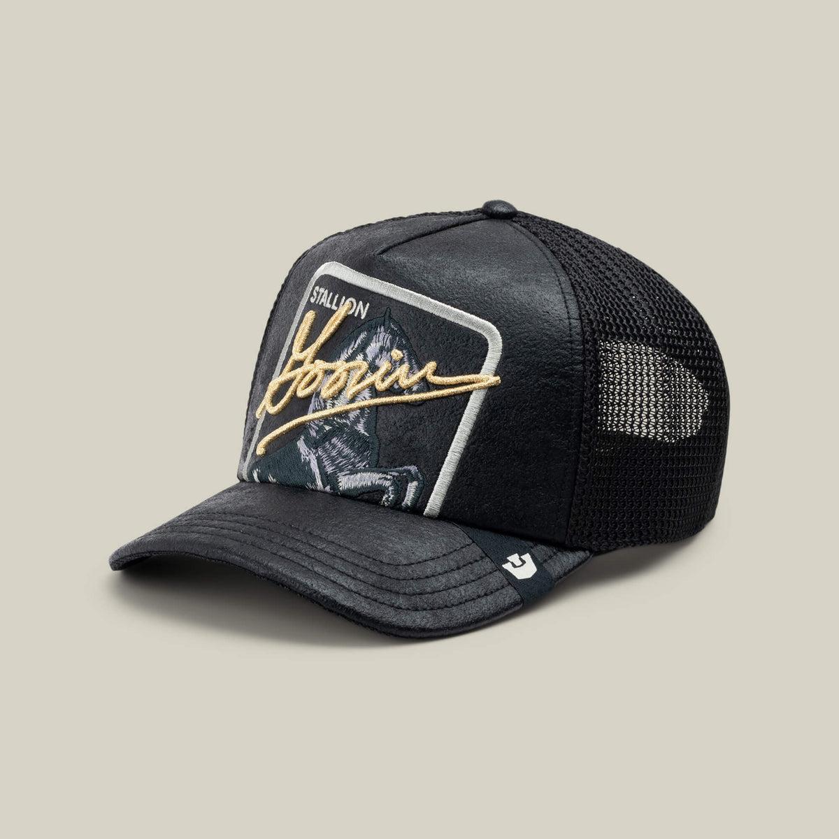 The NeoBrand STALLION by Goorin Bros. is a black trucker hat with mesh back, monochrome horse and rider embroidery, gold Hoozin script, and bold STALLION text—ideal to pair with blacked-out sneakers for a sleek style.