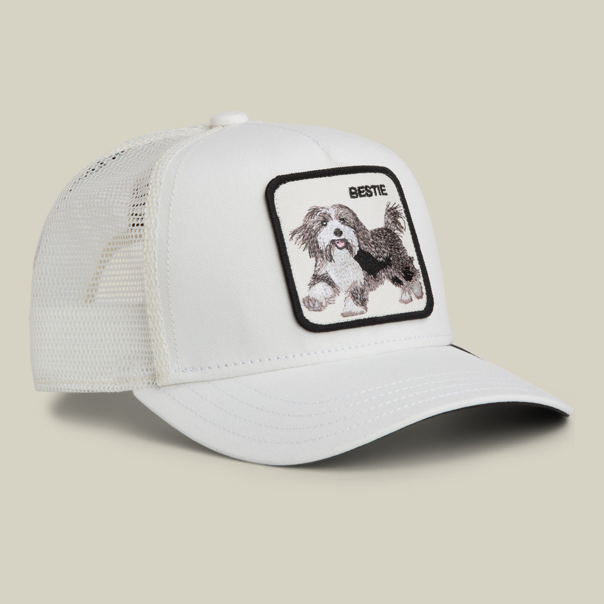 The Goorin Bros. Bestie Trucker is a white mesh trucker cap with a patch featuring an embroidered running dog and the word “BESTIE” above it.