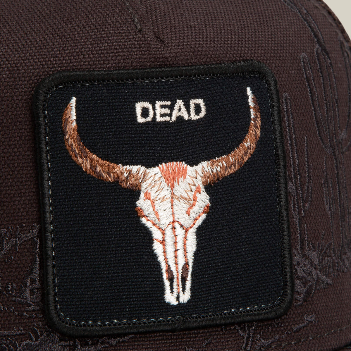 A close-up of the Goorin Bros. Badlands Skull patch, featuring an embroidered bull skull and the word "DEAD" in white letters on a dark brown fabric background.