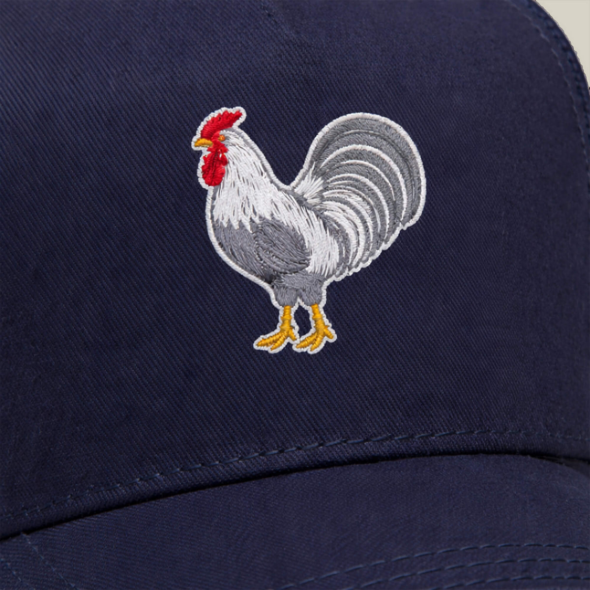 The Goorin Bros. Gone Cockmaxxing is a navy blue, full-size hat featuring an embroidered rooster in white, grey, yellow, and red—an instantly recognizable statement piece.