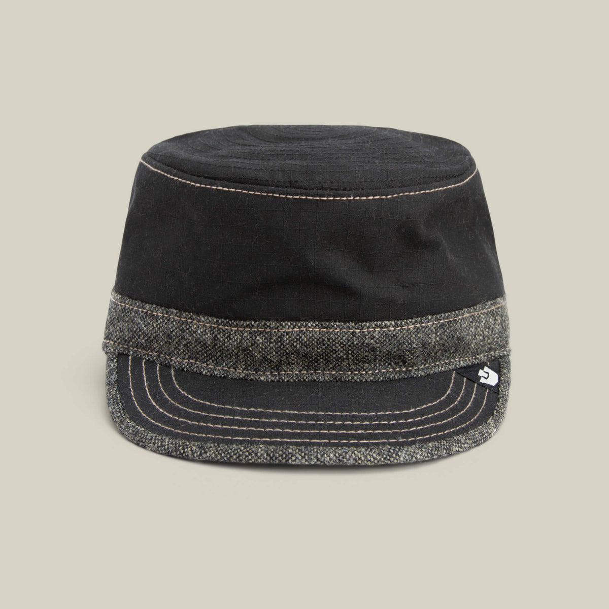 The Goorin Bros. Ampere cap in VOID features a flat top, short brim, and a grey tweed band at the base, shown against a plain beige background.