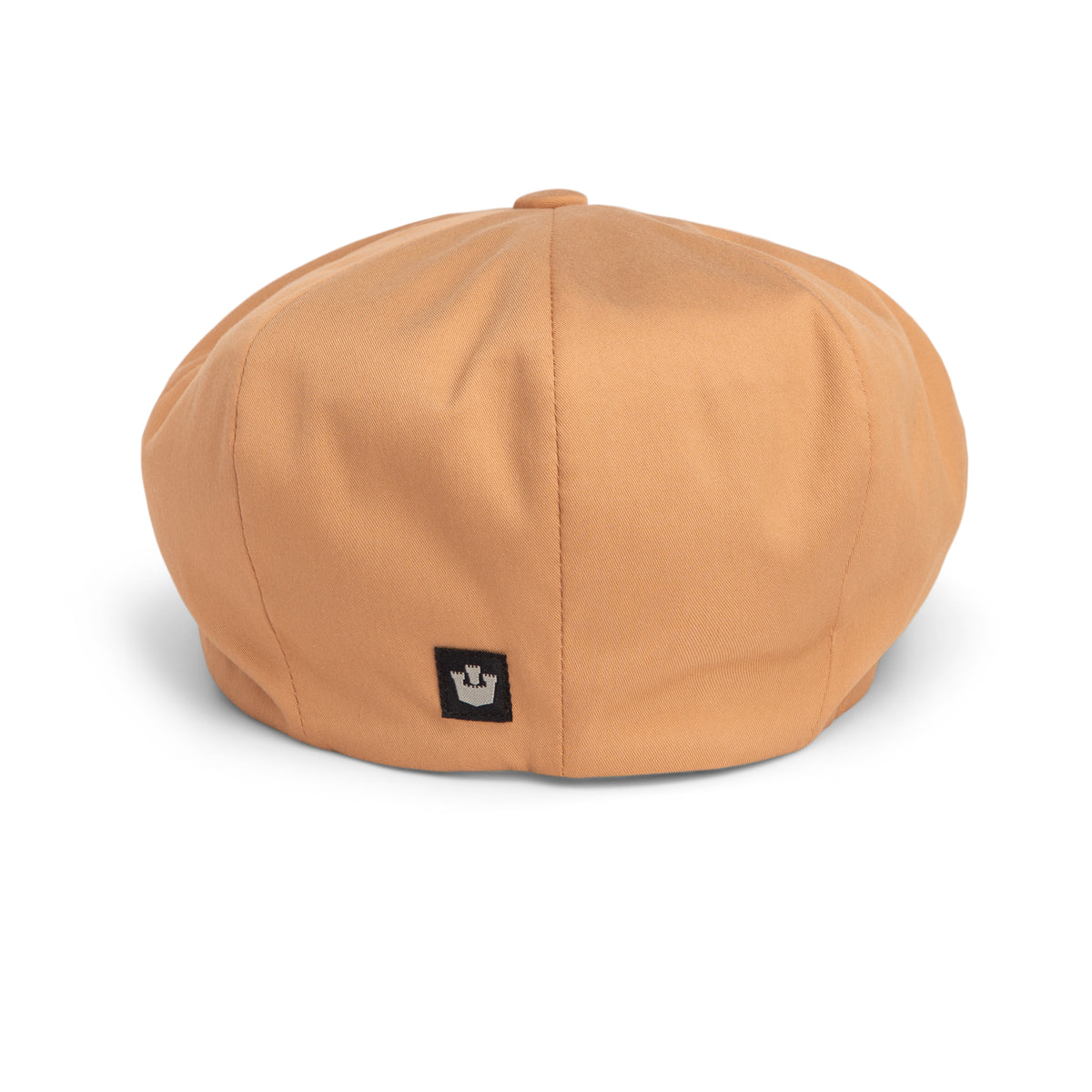 The Goorin Bros. Chopping Block is a tan beret with a unique shape, featuring a small black rectangular patch adorned with a white crown on the back, displayed against a white background.