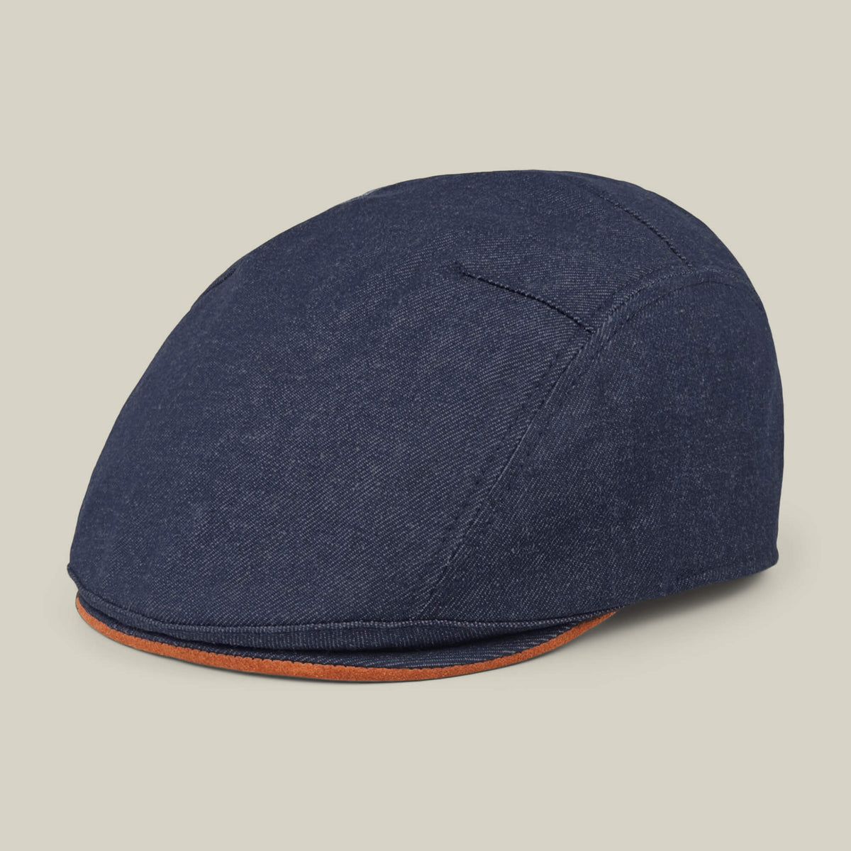 The Goorin Bros. Ashfield is a blue cotton suede flat cap with visible stitching and a brown-trimmed brim, made in the USA, shown against a plain light background.