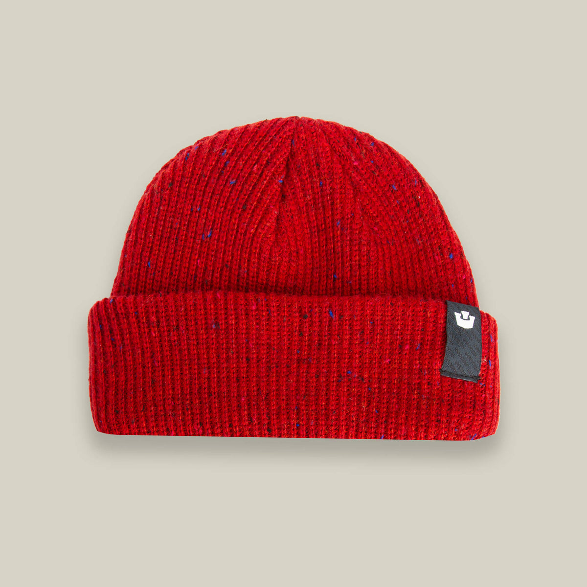 The Goorin Bros. "No Comply" beanie is a warm, red knit hat with a folded brim and a small black tag on the right side, shown on a light beige background.