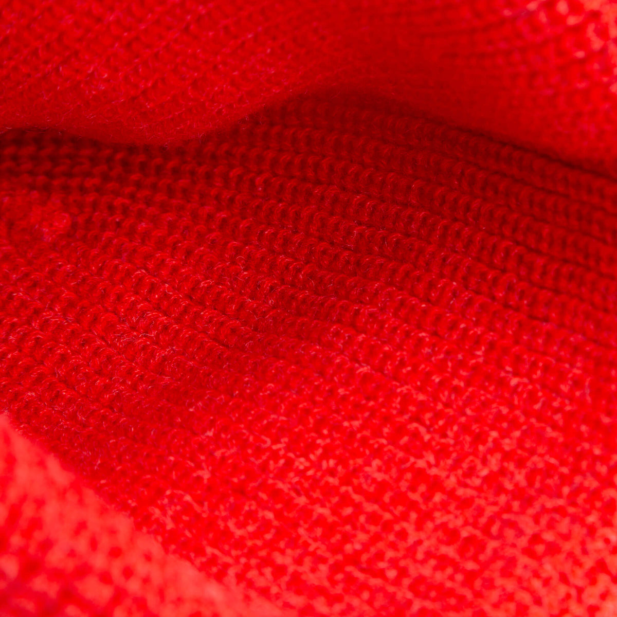 Close-up of a red knit fabric from The Nonstop Beanie by Goorin Bros., highlighting detailed stitching and cozy texture—ideal for a stylish winter hat.