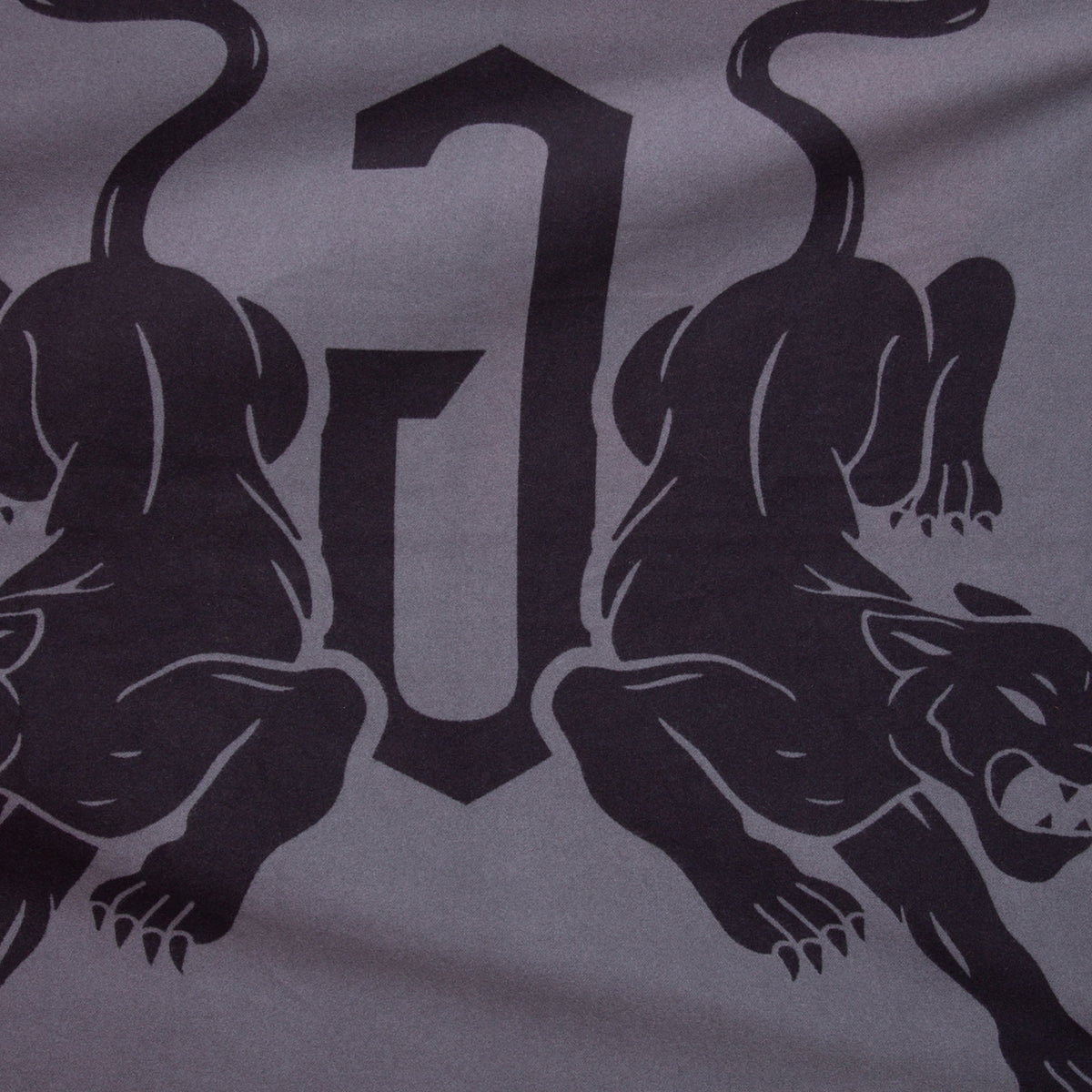 Two stylized panthers face away from each other with a bold, abstract “J” between them on a gray background—perfectly featured on the Goorin Bros. Panther Crest Blanket to add striking style to any throw blanket collection.