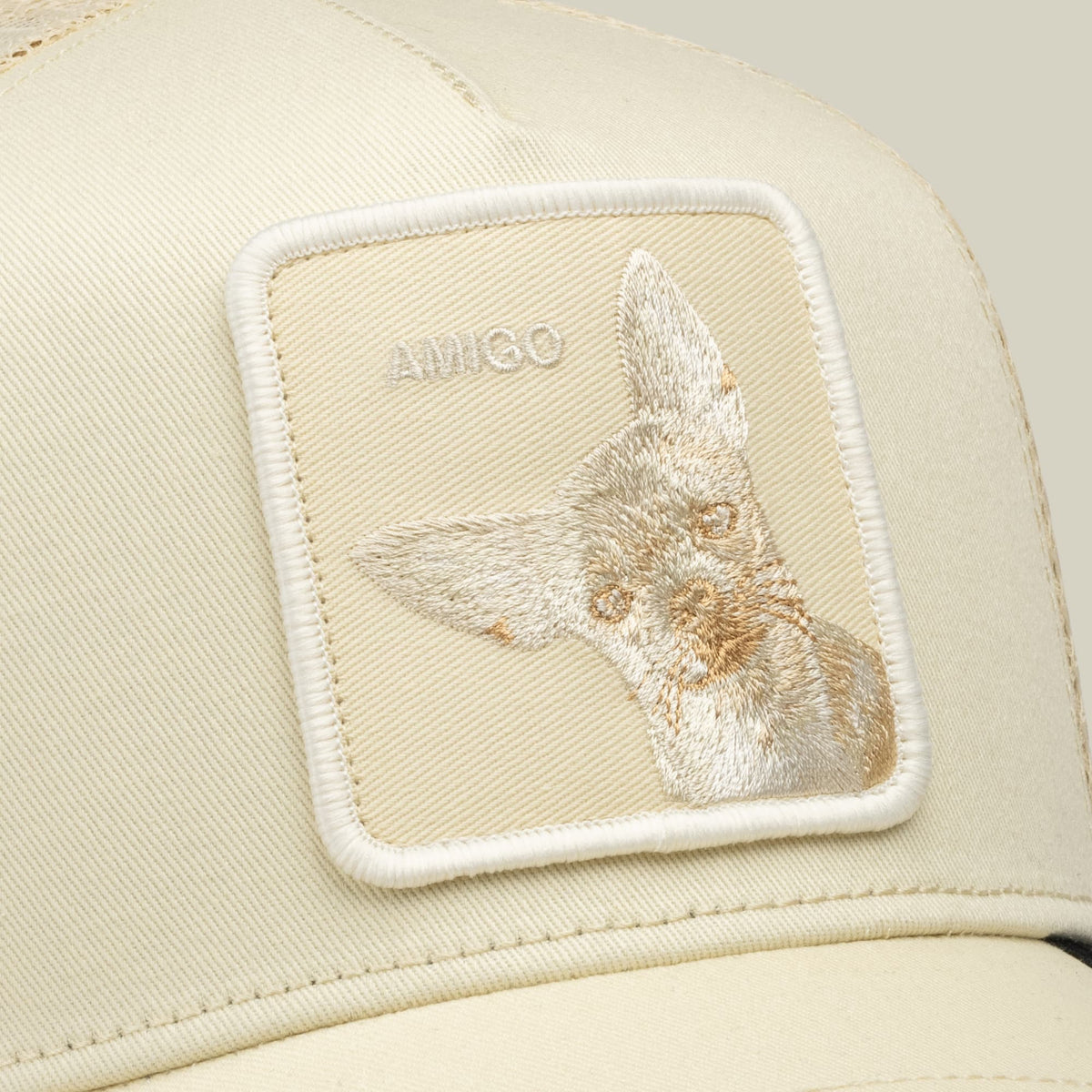 The Goorin Bros. Tonal Amigo Mini is a cream trucker hat featuring an embroidered patch with a tan and white llama design and Goorin branding on the front panel.