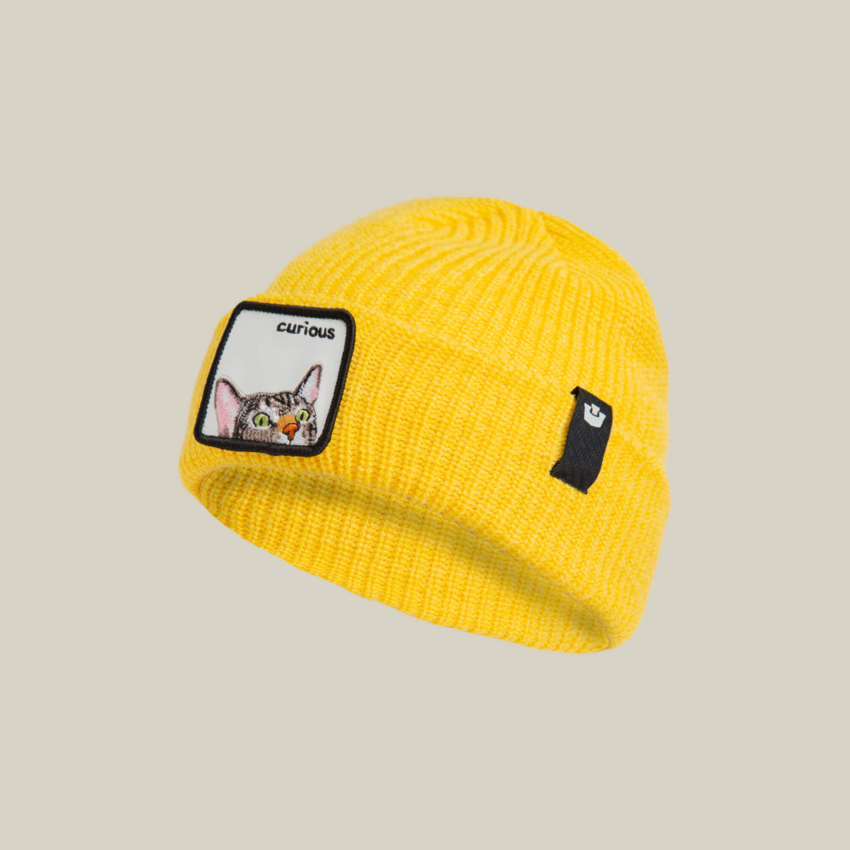 The Curious Beanie Mini by Goorin Bros. is a yellow knit kids beanie with a "curious" cat patch and a small black rectangular patch on the front.