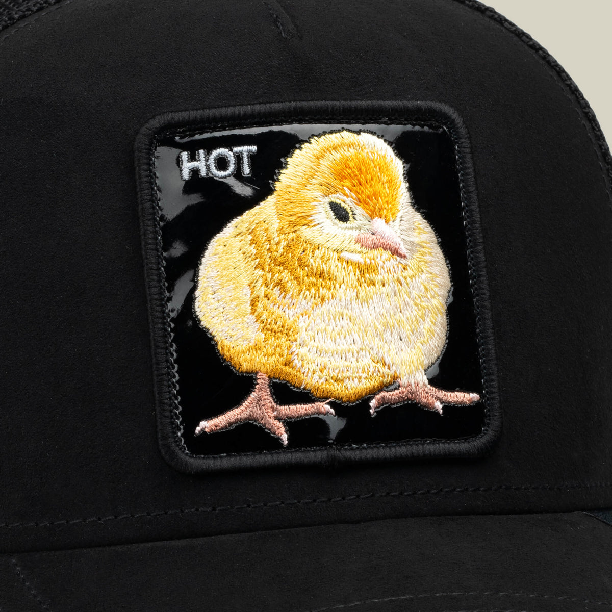 The Black Out Chick hat by Goorin Bros. showcases a yellow chick patch with an embroidered chick and the word “HOT” in white text at the top left corner, delivering a bold look inspired by the classic Goorin trucker style.