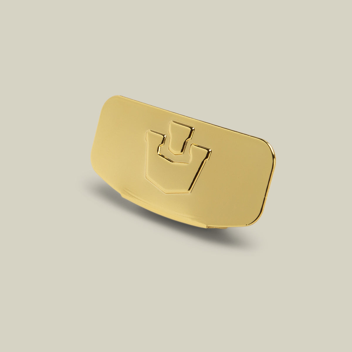 A rectangular Castle CapLoc by Goorin Bros., crafted from zinc alloy with beveled edges and an embossed abstract symbol at its center, serves as a stylish hat accessory, displayed against an off-white background.