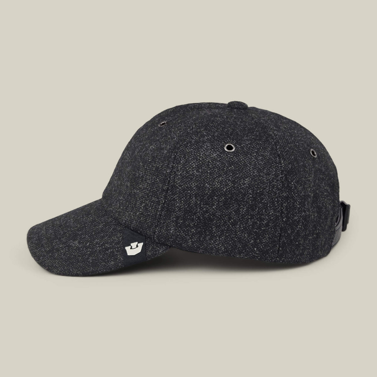 The Goorin Bros. Valmont is a dark grey textured wool baseball cap featuring a small metallic logo tag on the brim, silver eyelets, and an adjustable strap at the back, made in the USA and shown against a plain light beige background.