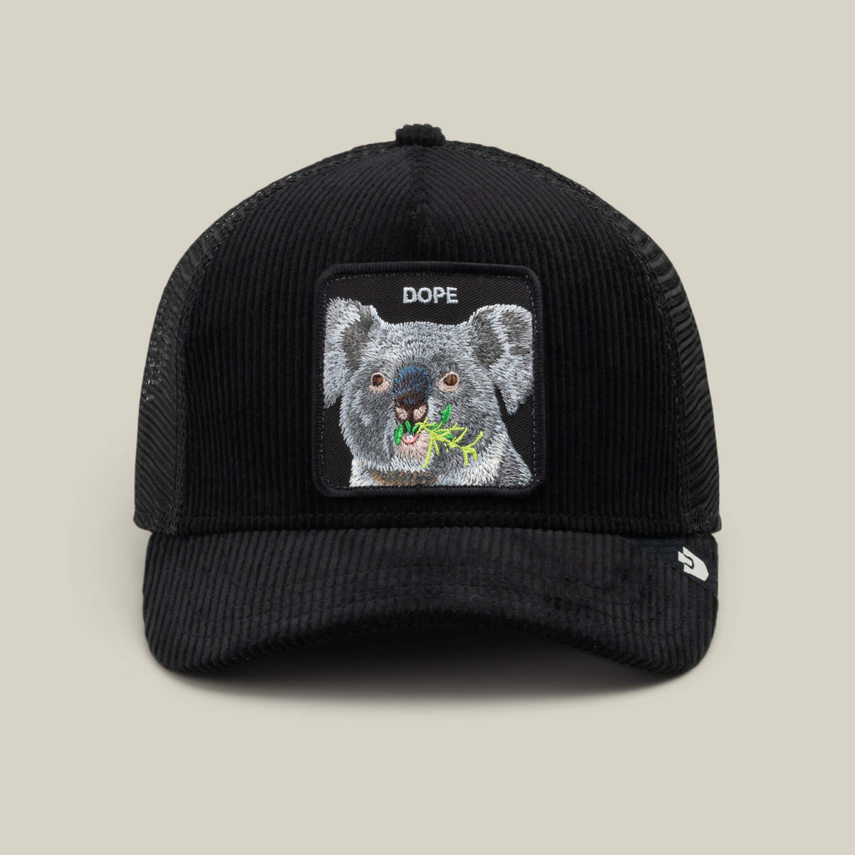 The Goorin Bros. Corduroy Dope is a black corduroy trucker hat with a mesh back and features an embroidered patch of a koala eating leaves, with the word “DOPE” above the image.