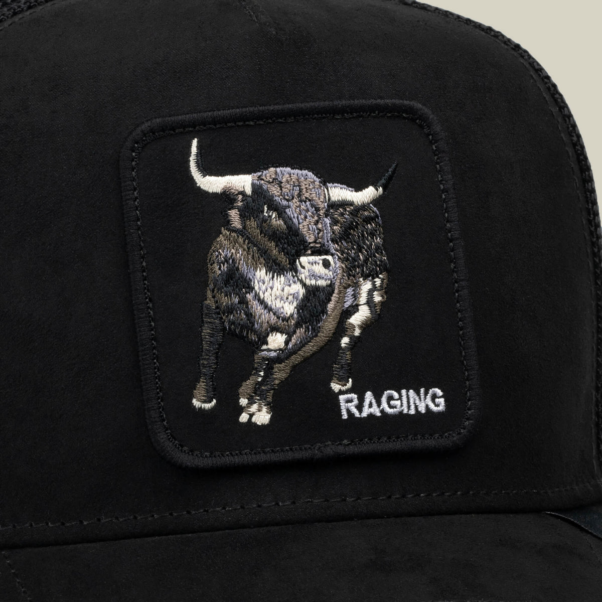 A close-up of the Goorin Bros. Suede Bull cap, showcasing an embroidered patch of a RAGING Bull and the word “RAGING” in white text, crafted from durable polyester for a sleek addition to your athletic wear collection.