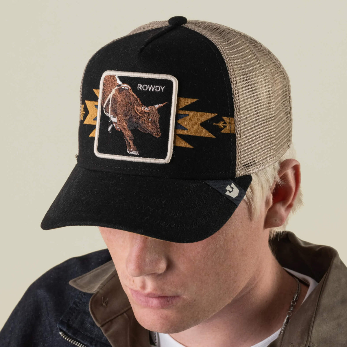 A person wearing the Goorin Bros. Canyon Rowdy black and tan mesh back trucker hat, featuring a southwestern bull patch, channels serious bull energy while looking down.