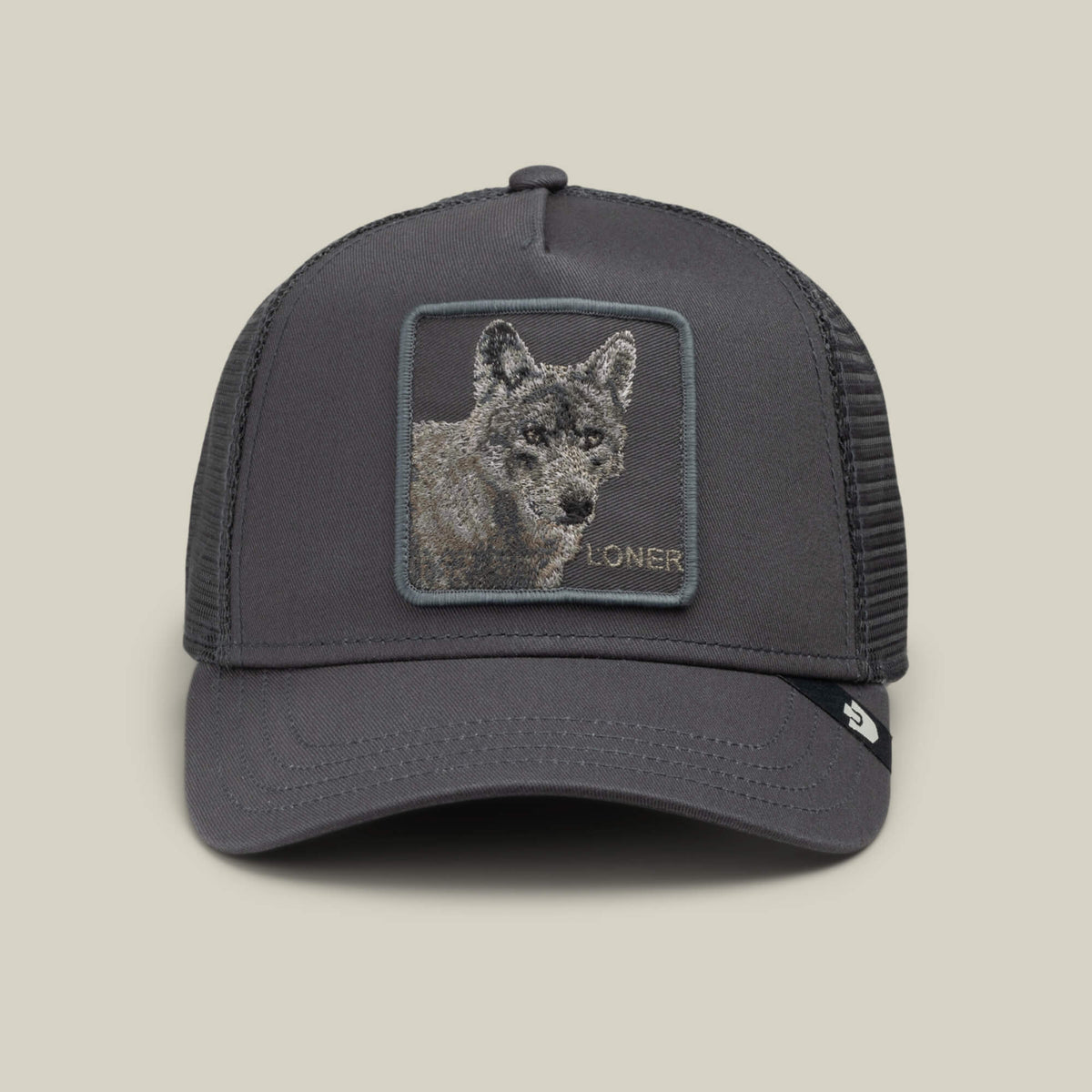 The Goorin Bros. Circle of Life – Loner is a gray mesh trucker cap, featuring an embroidered wolf patch with the word “LONER” beneath the wolf’s face on the front panel. Displayed against a light beige background, this stylish snapback hat stands out for its unique design.