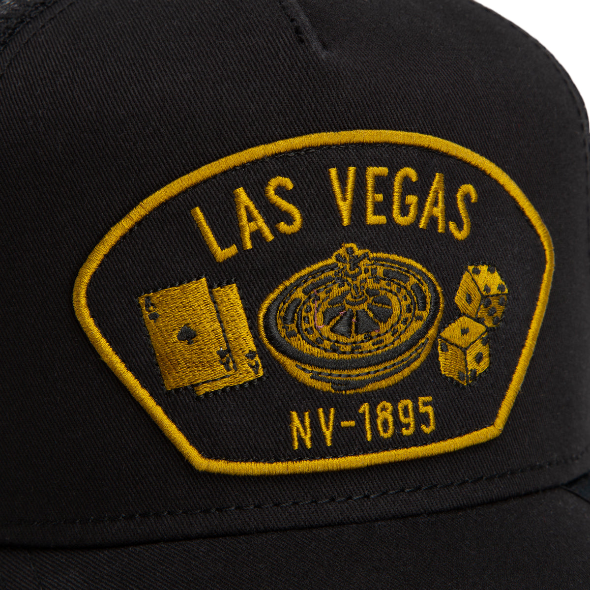 Black mesh-back trucker hat from Goorin Bros. featuring a yellow embroidered Las Vegas NV-1895 patch with playing cards, a roulette wheel, and dice—perfect for any Las Vegas enthusiast.
