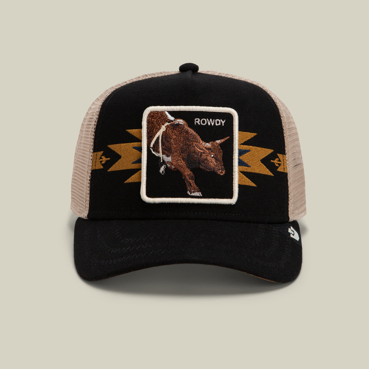 The Goorin Bros. Canyon Rowdy is a black and beige mesh trucker hat featuring a gold geometric pattern on the front panel, along with a patch displaying a bull and the word “ROWDY”—ideal for anyone who loves bold style and dynamic energy.