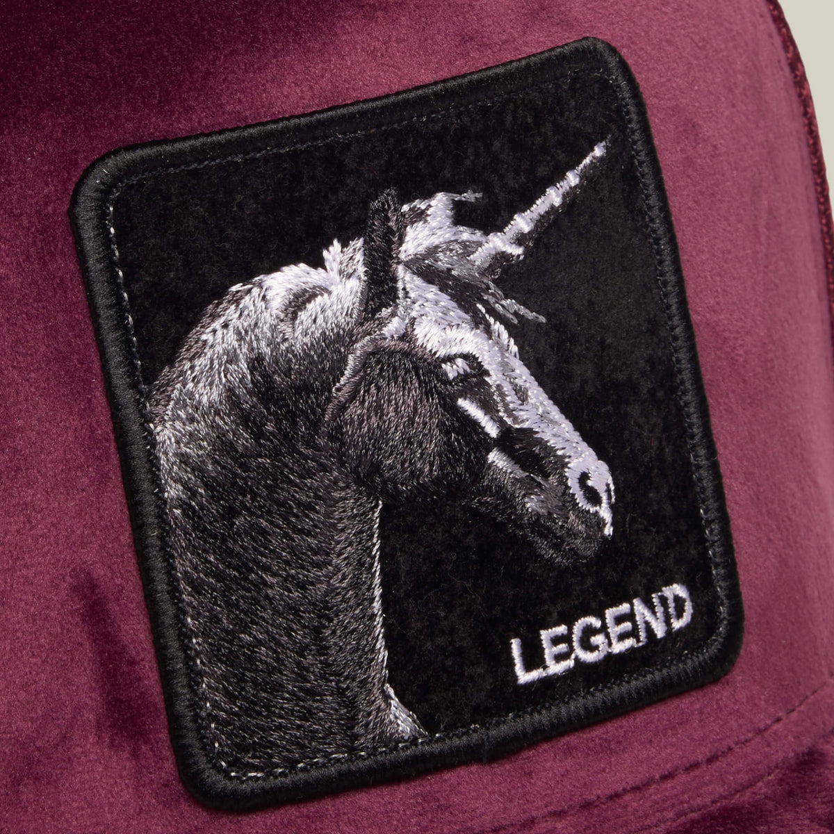 The Velour Legend by Goorin Bros. is an embroidered unicorn patch on a luxurious burgundy velour fabric, featuring the word “LEGEND.”.