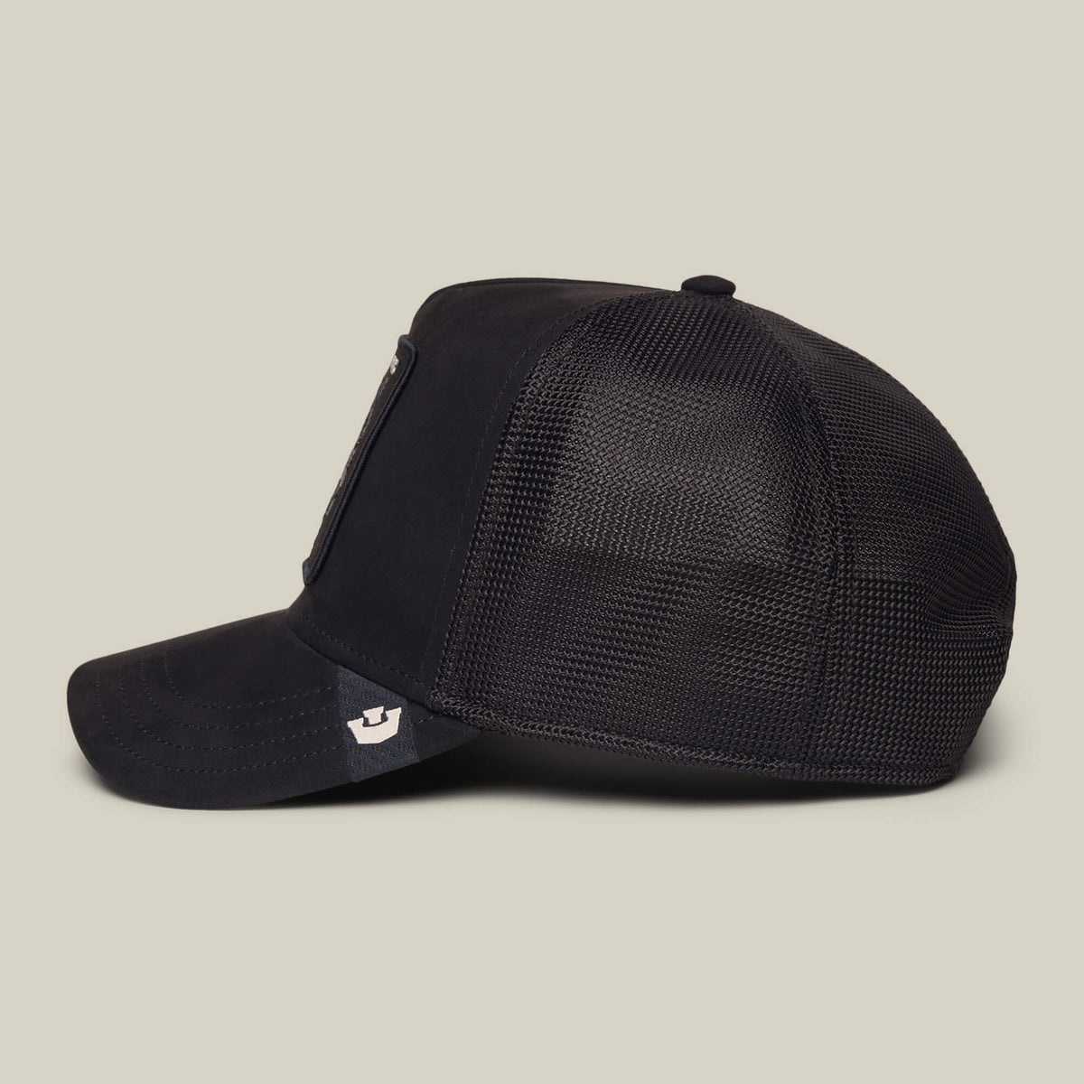The Goorin Bros. Suede Sheep trucker hat is displayed in a side profile view against a plain light background. The bill is accented with a small, light-colored black sheep patch on the left side, adding a distinctive detail that makes this black and white cap stand out.
