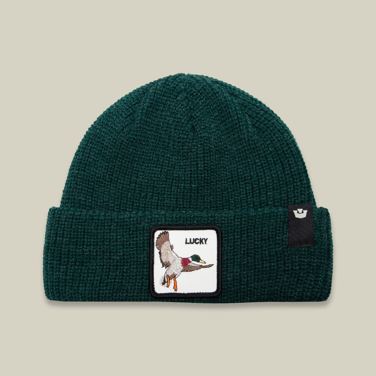 The Lucky Duck Beanie by Goorin Bros. comes in a deep forest green and features a folded brim, an embroidered patch of a flying duck with the word “LUCKY” on the front, and a discreet black tag on the side. This warm knit beanie is both stylish and cozy for any season.
