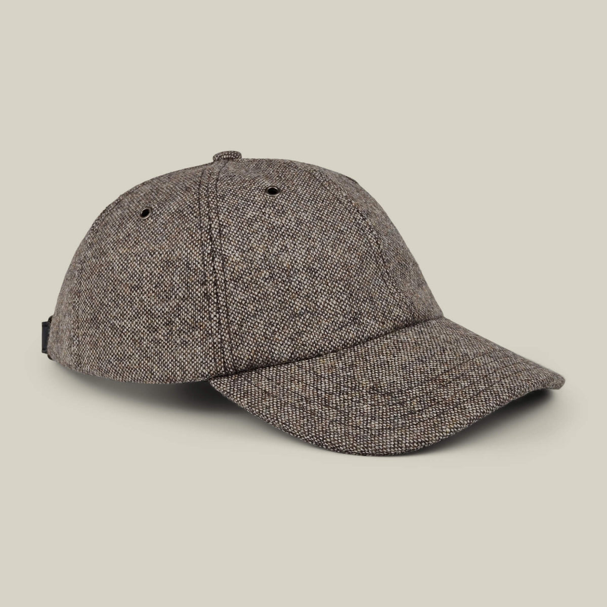 The Valmont by Goorin Bros. is a brown tweed wool baseball cap featuring a curved brim and a button on top, made in the USA and displayed against a plain beige background.