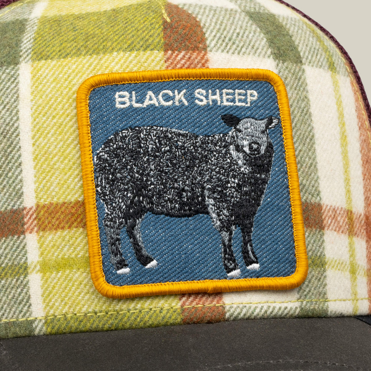 The Brit Sheep by Goorin Bros. is a fall plaid trucker hat featuring a sewn BLACK SHEEP patch, with a black sheep and the words “BLACK SHEEP” in white text above it. Crafted from a classic wool blend, this hat effortlessly adds character to any outfit.
