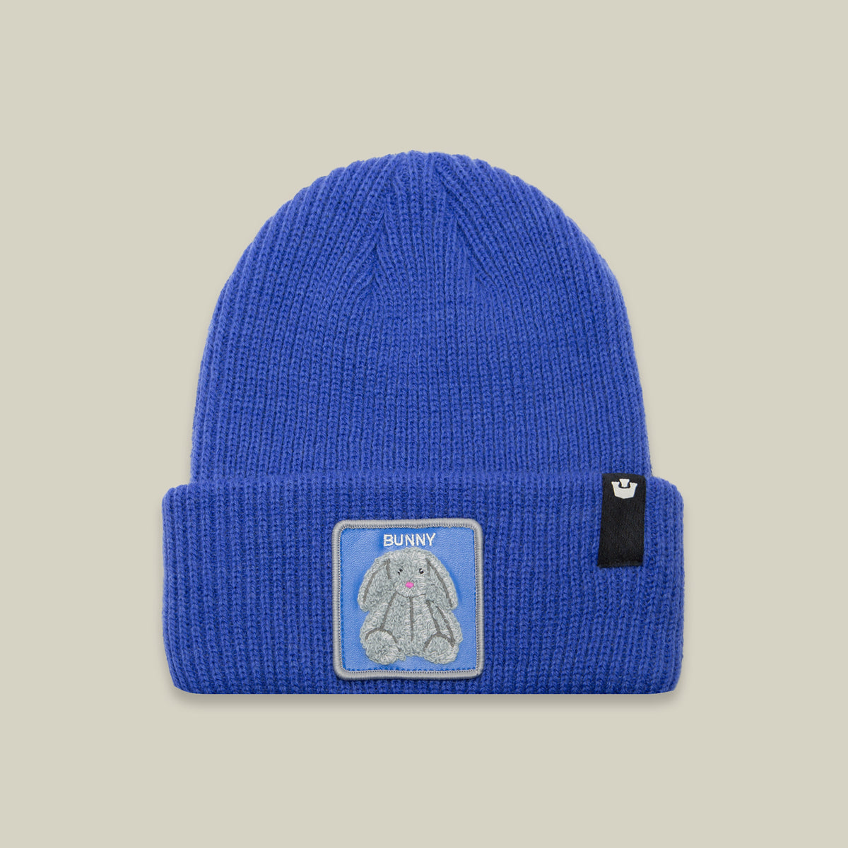 The Double Stuffed - Bunny Beanie by Goorin Bros. is a bright blue rib-knit cuffed cap, featuring a patch of a gray cartoon bunny with the word “BUNNY” on the front, and finished with a small black Goorin tag on the cuff.