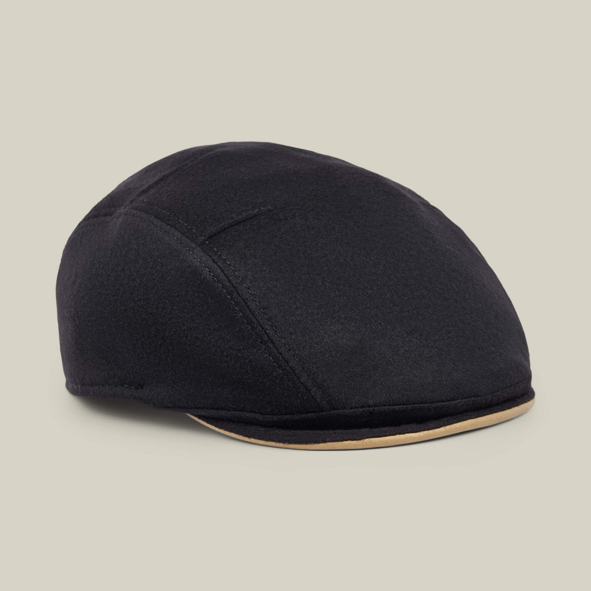 The Goorin Bros. “Cornerstone” is a black wool flat cap, handmade in New Jersey, featuring subtle stitched details and a contrasting beige trim along the brim, displayed on a neutral background.