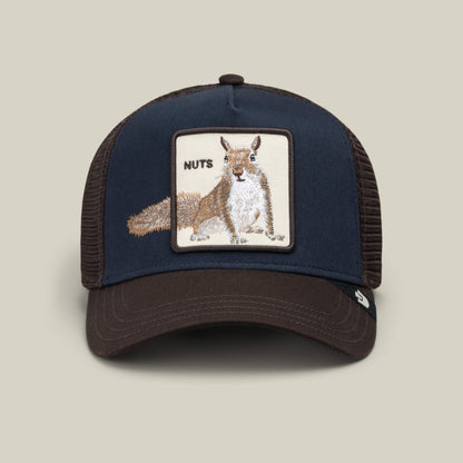 The Over the Line Squirrel trucker hat by Goorin Bros. features a navy and brown design with a mesh back, highlighted by an embroidered patch of a squirrel and the word “NUTS” on the front, making this playful accessory both stylish and fun.