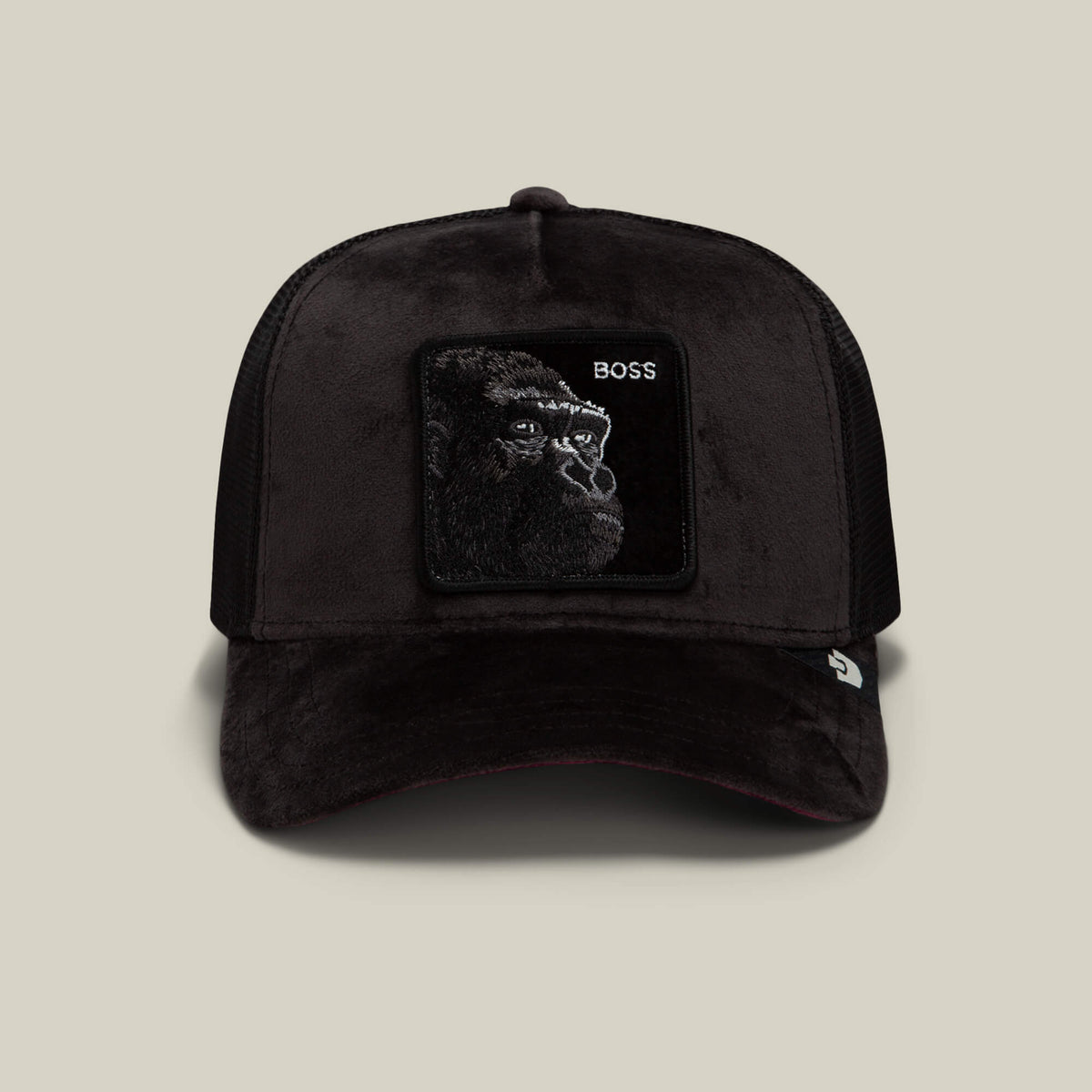 Introducing the Velour Boss by Goorin Bros.—a black velour trucker baseball cap featuring a square patch with a gorilla face and the word “BOSS” embroidered on the front. This stylish polyester cap is showcased against a plain, light background.