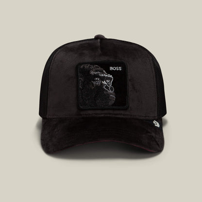 Introducing the Velour Boss by Goorin Bros.—a black velour trucker baseball cap featuring a square patch with a gorilla face and the word “BOSS” embroidered on the front. This stylish polyester cap is showcased against a plain, light background.