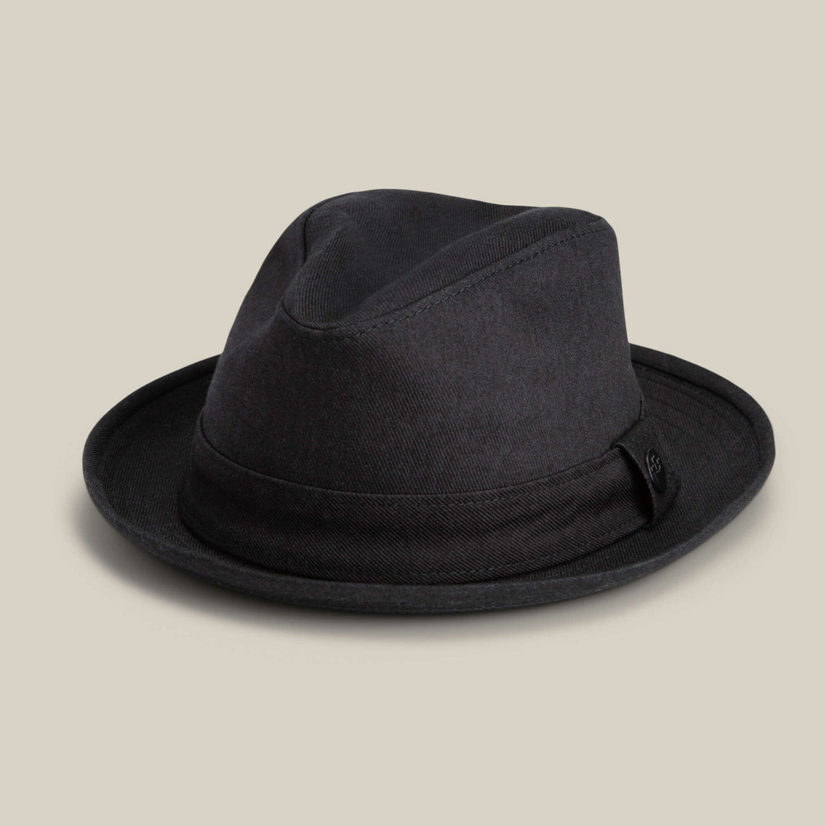 The Goorin Bros. Big Stepper is a black fedora hat with a short brim and decorative band, stylishly displayed against a plain beige background.
