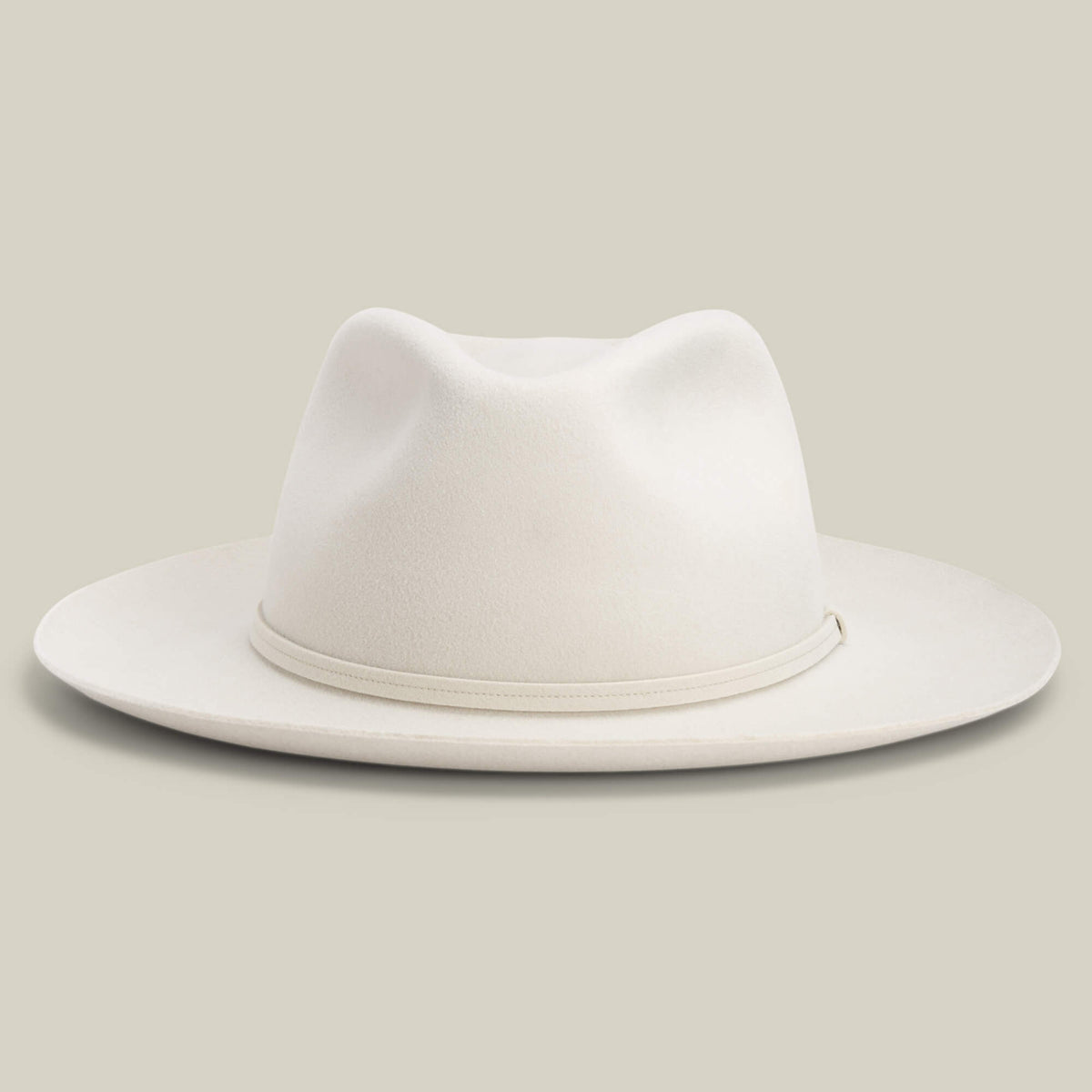 The Night Hawk by Goorin Bros. is a cream-colored fedora with a teardrop crown, wide snap brim, and matching hatband—an elegant all-season hat, shown against a plain light background.