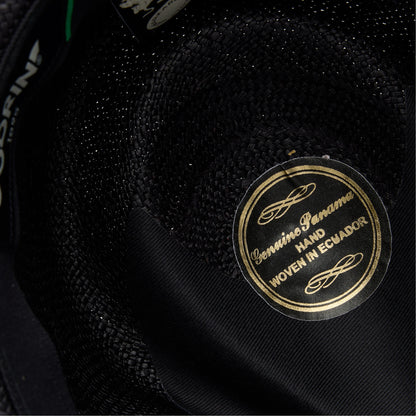 Close-up of the inside of a John Sr. black toquilla teardrop fedora by Goorin Bros., featuring a gold label reading Genuine Panama Hand Woven in Ecuador and offering 50 UPF sun protection.
