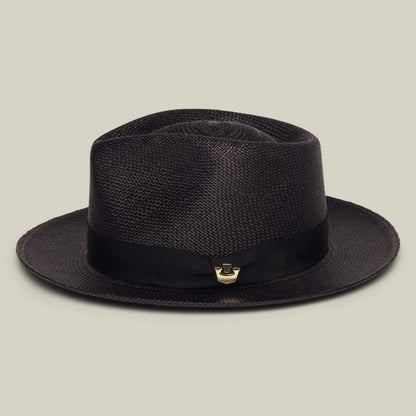 The John Sr. by Goorin Bros. is a dark brown toquilla teardrop fedora with a wide brim, black ribbon band, 50 UPF sun protection, and a small gold accent, shown on a plain light background.