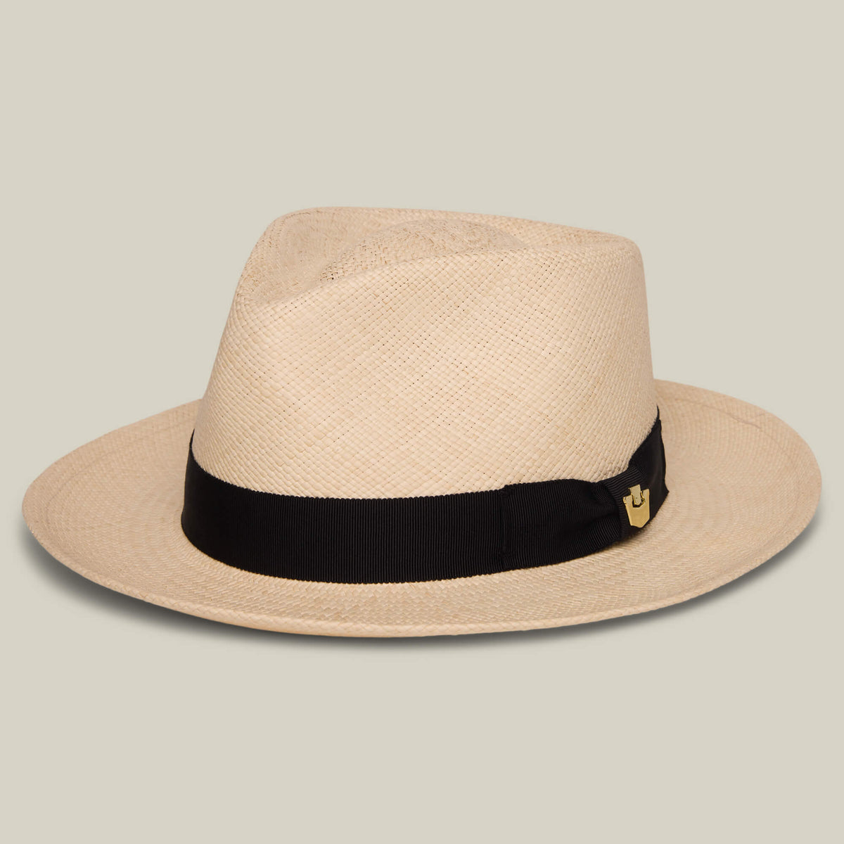 The John Sr. by Goorin Bros. is a beige toquilla teardrop fedora with a black band, small gold emblem, and 50 UPF sun protection, shown on a plain light background.