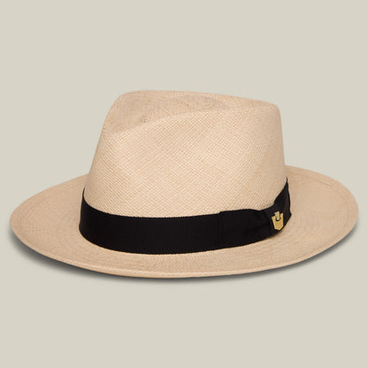 The John Sr. by Goorin Bros. is a beige toquilla teardrop fedora with a black band, small gold emblem, and 50 UPF sun protection, shown on a plain light background.
