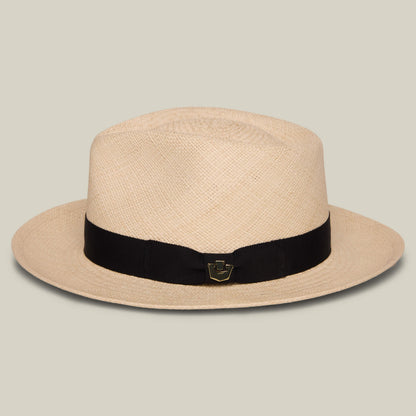 The Goorin Bros. John Sr. is a beige toquilla teardrop fedora with a wide brim, black ribbon band, small gold emblem on the front, and 50 UPF sun protection for stylish and safe wear.