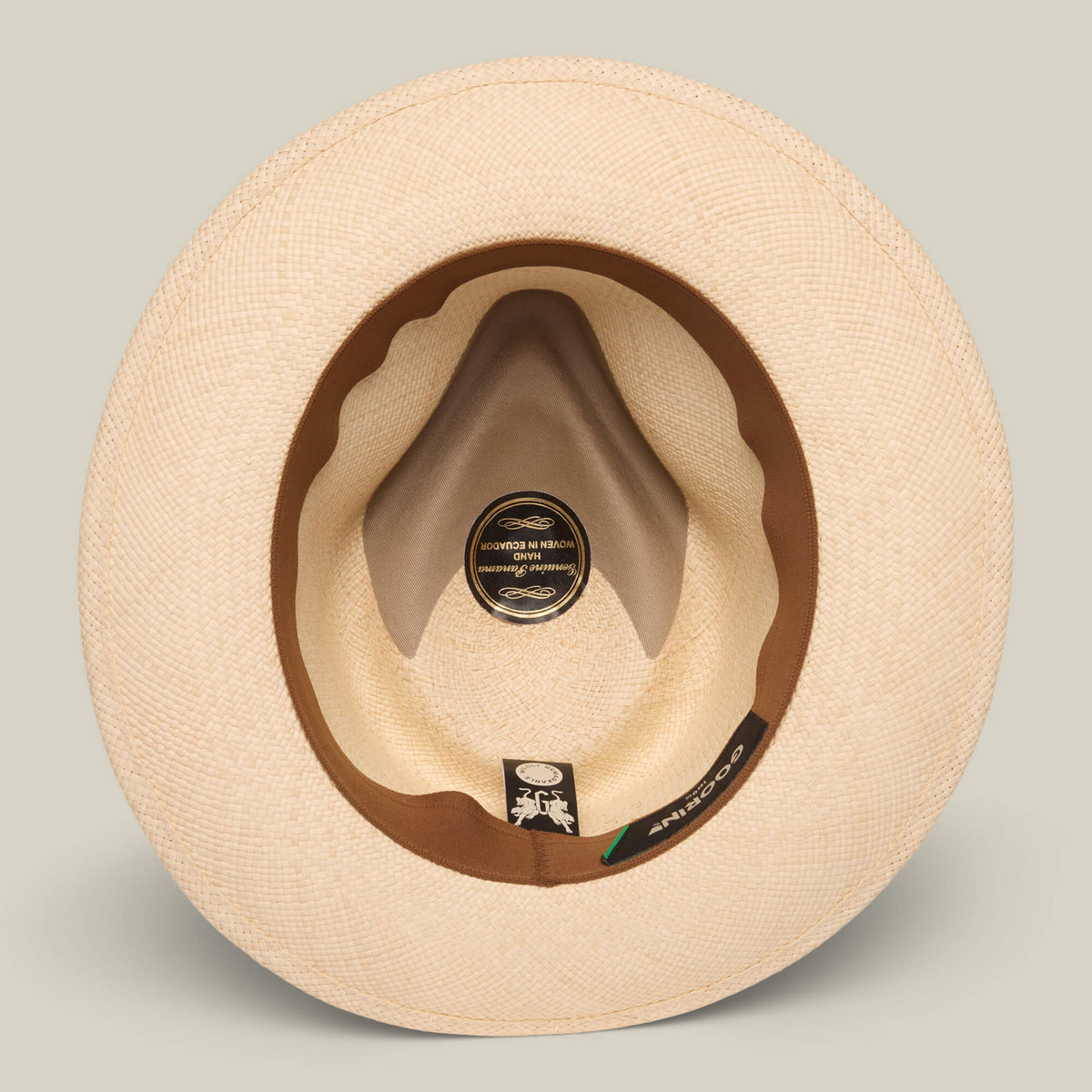 A top-down view of the John Sr. teardrop fedora by Goorin Bros., featuring a beige toquilla finish, brown sweatband, visible brand labels inside the brim, and 50 UPF sun protection for comfort and style.